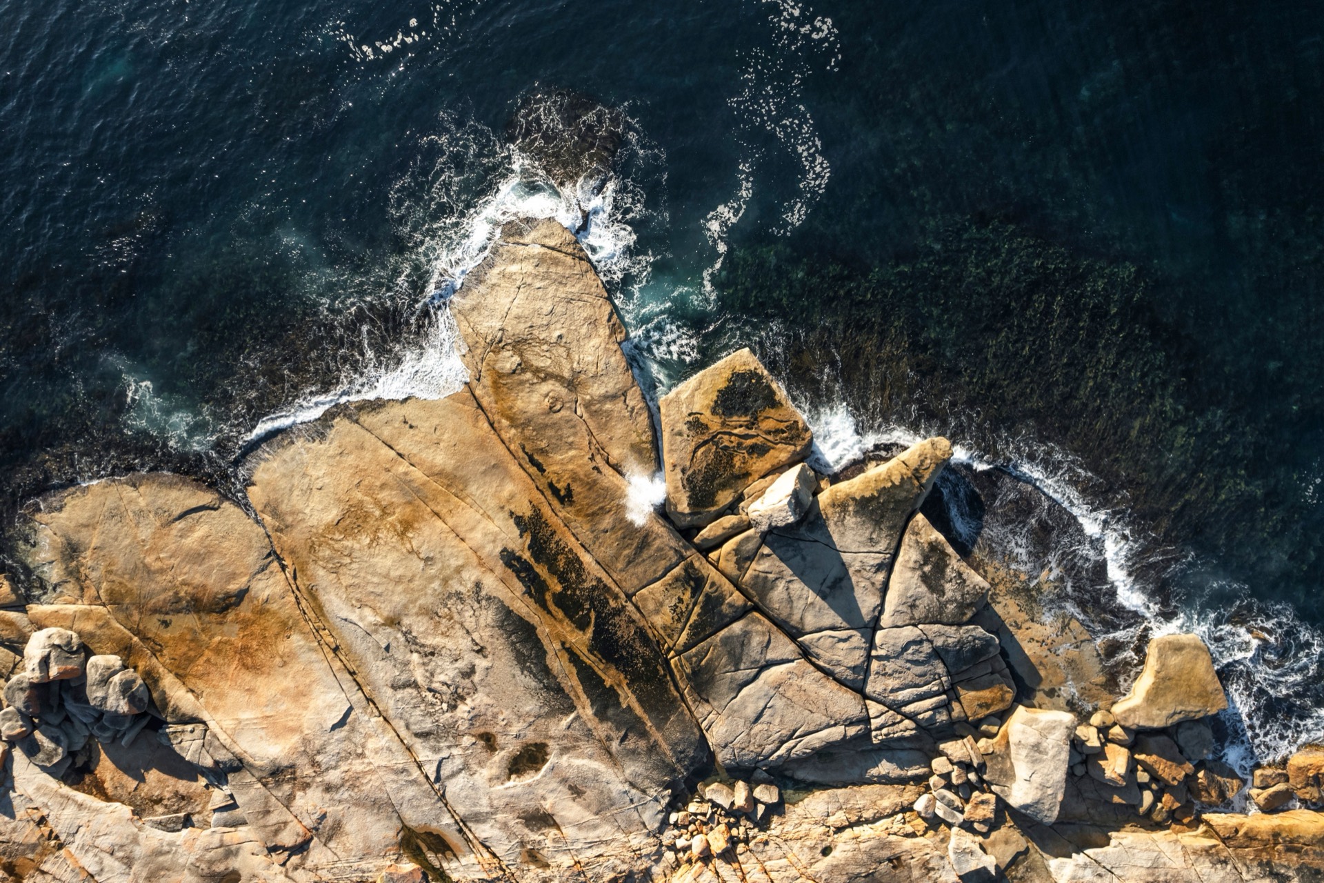 Aerial view of swell forcing through the rocky coastline at the Bicheno Blowhole