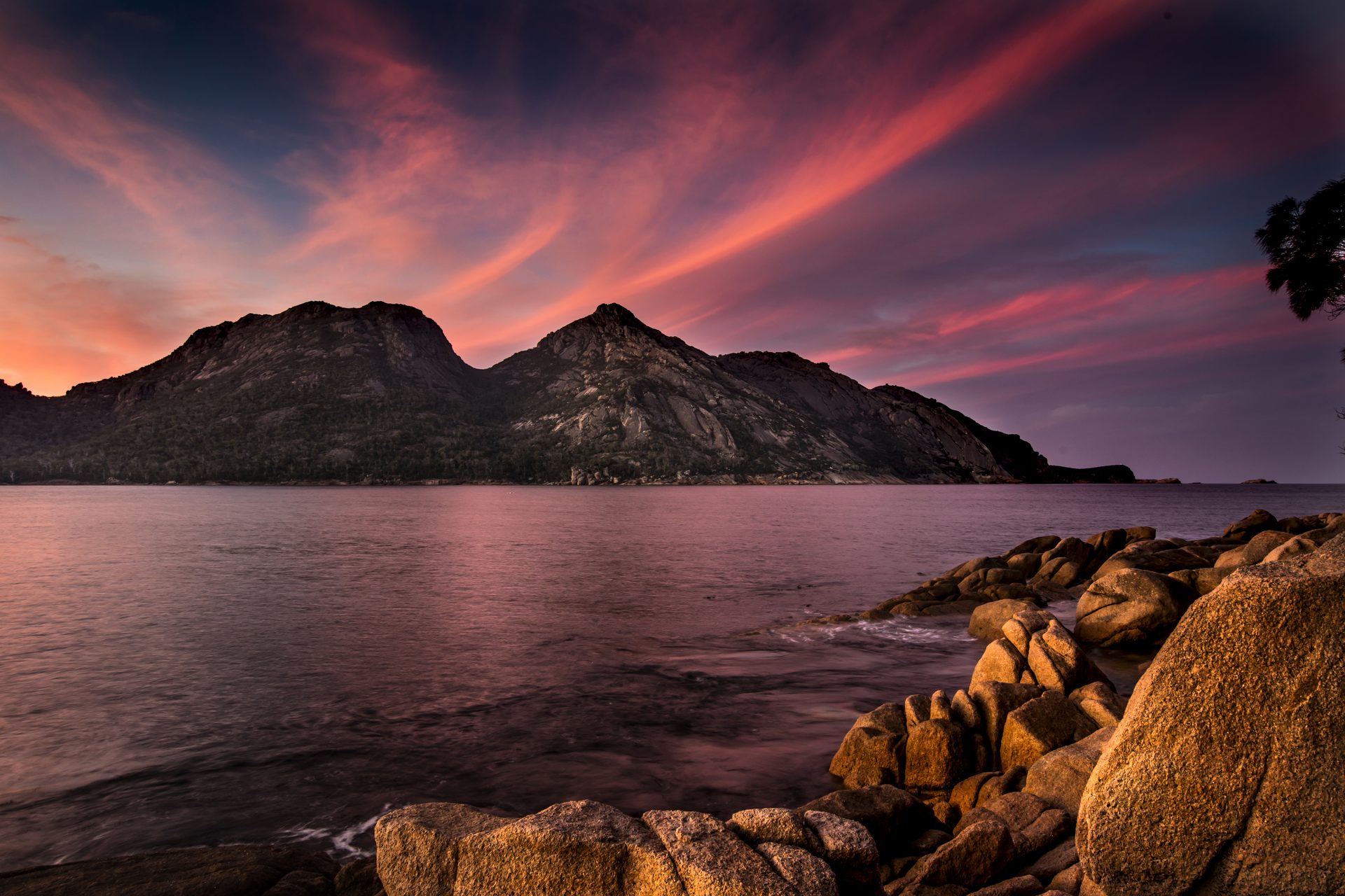 The Hazards at sunset from Coles Bay, with granite boulders in the foreground