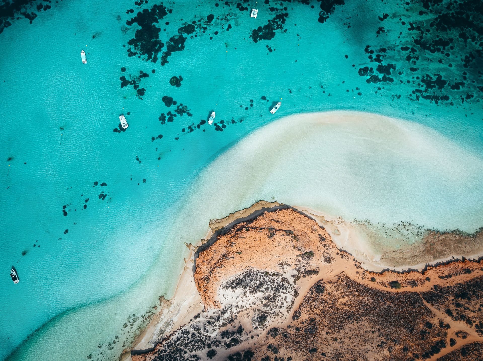 Aerial view of turquoise reef water, white sand and red earth at Coral Bay